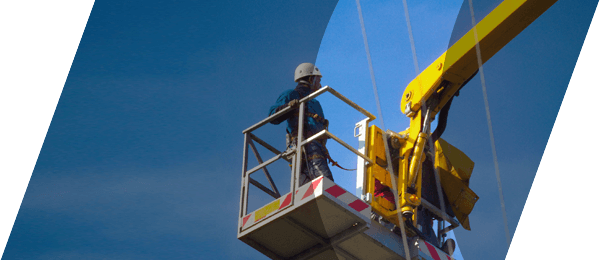 In the foreground a worker on a construction crane, and on the background a clear blue sky