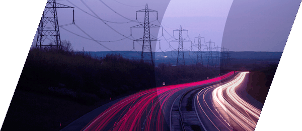 Red and bright yellow light trails of vechicles on a motorway and power cables at dusk
