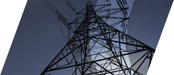 A high contrast and dramatic photograph of a transmission tower with power line cables, photographed from a low angle in a diagonal composition